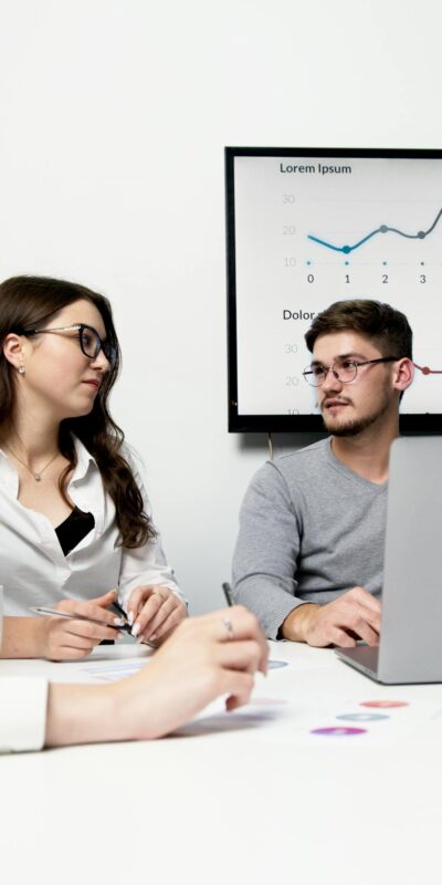 Man and Woman Sitting at Table Using Laptop Computer